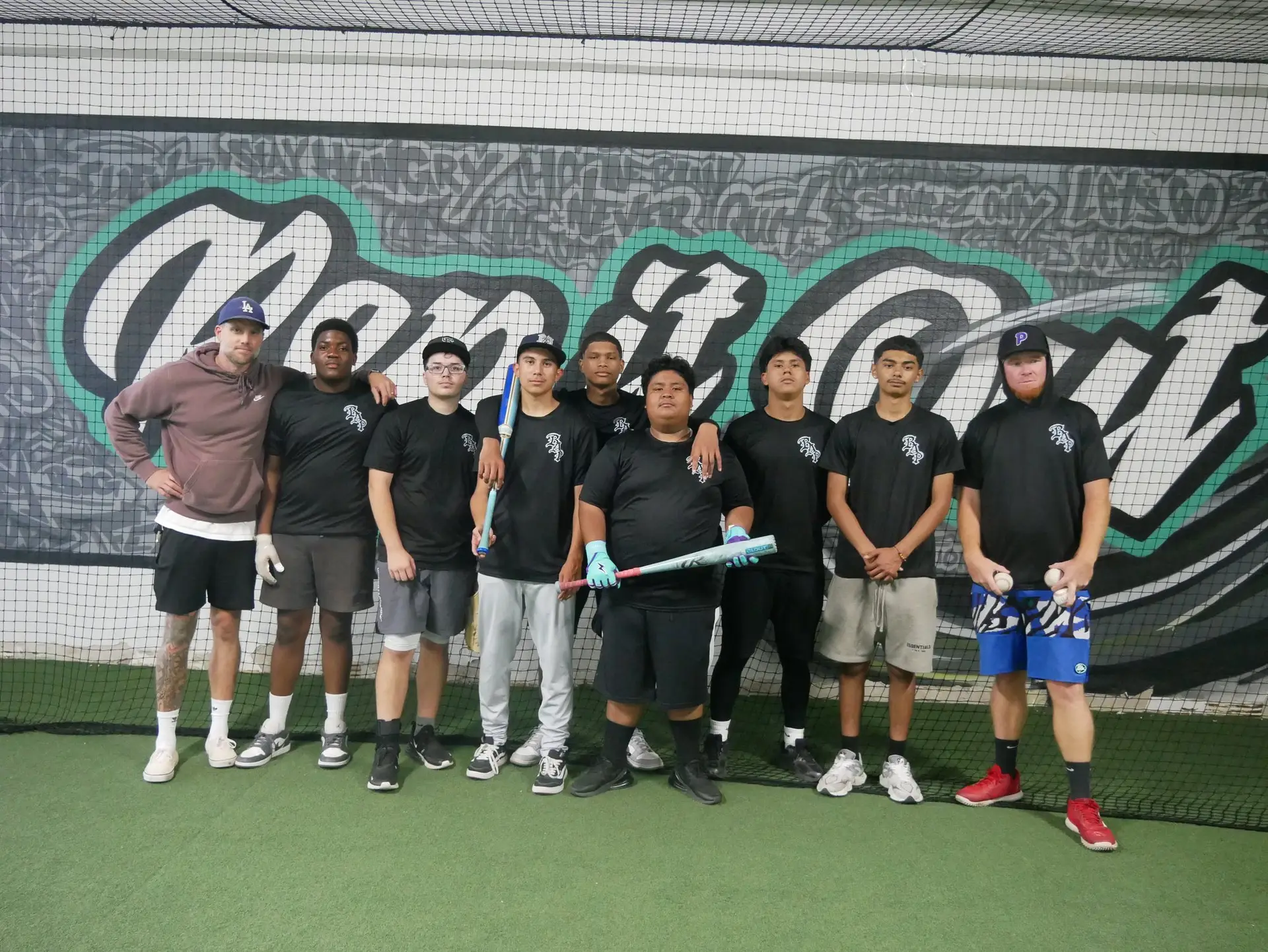 Baseball Access Project players and coaches in front of the Rep It Out mural