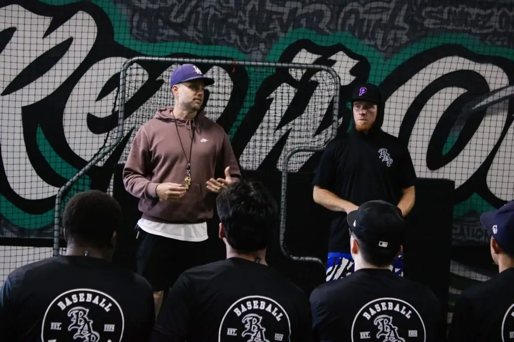 BAP coach talking with players in front of the mural